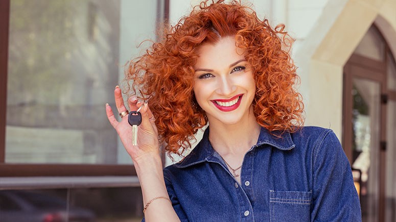 Red head young woman holding car keys while smiling
